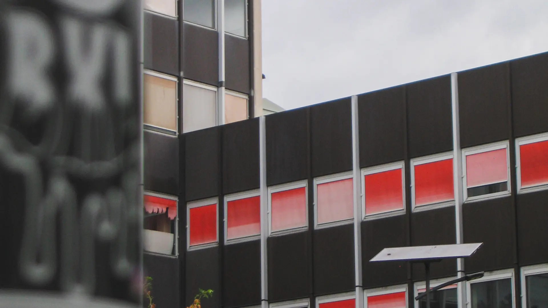 Photographie architecturale d'une façade d'immeuble aux fenêtres rouges à Bruxelles